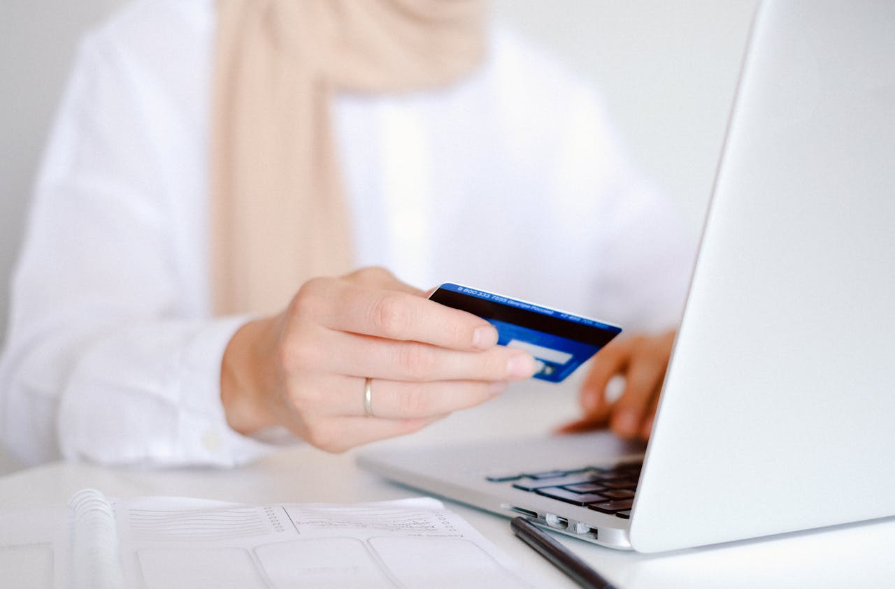Image of someone holding a credit card at a computer, as if online shopping